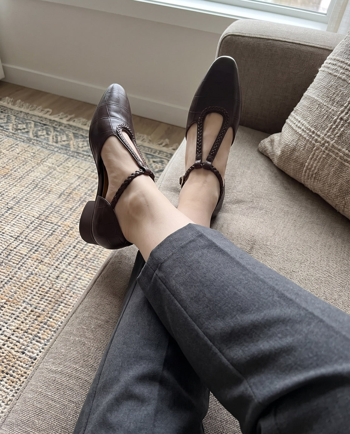 Braune Schuhe mit geflochtenem Riemen, Füsse auf einem Sofa